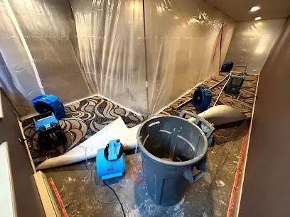 Containment plastic, air movers and a rolled-back carpet drying a room in a Wheat Ridge home
