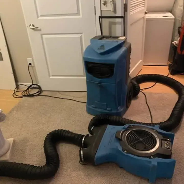 Dehumidifier and air mover pushing dry air through a duct into a bedroom