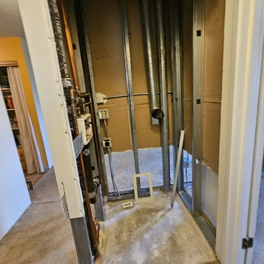 Wall opened to the studs around supply pipes after a burst pipe soaked the floor
